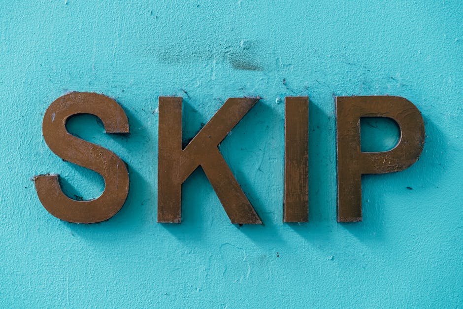 A close-up of three dark brown, three-dimensional metal letters spelling 'SKIP' mounted on a textured, painted turquoise wall. The letters are evenly spaced, with the 'S' on the left, 'K' in the center, and 'P' on the right, all in uppercase. The surface of the letters has a slightly rough, matte finish, and the wall behind them displays subtle unevenness and small imperfections in the paint. The scene is evenly lit, highlighting the contrast between the dark metal and vibrant background, suggesting a professional signage display often associated with waste management or skip hire services, which align with alternative rubbish removal options. The image emphasizes clarity and simplicity, making it suitable for contexts involving waste collection, skip permits, or independent rubbish handling services by companies such as Rubbish Collection Lewisham.